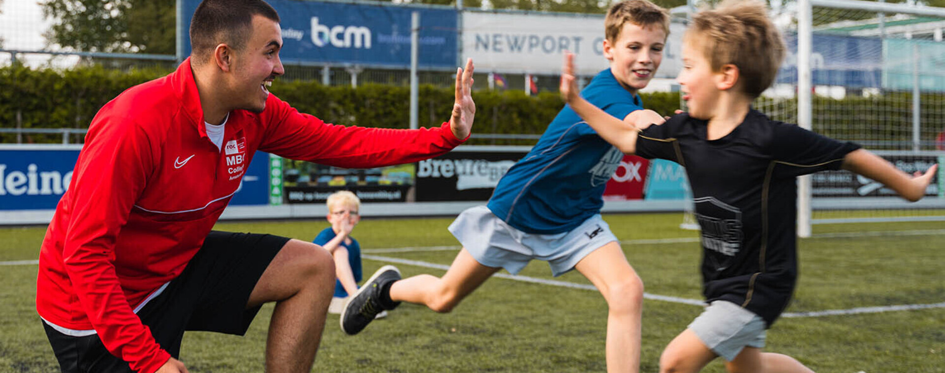 Coach geeft een high-five aan twee kleine voetballertjes