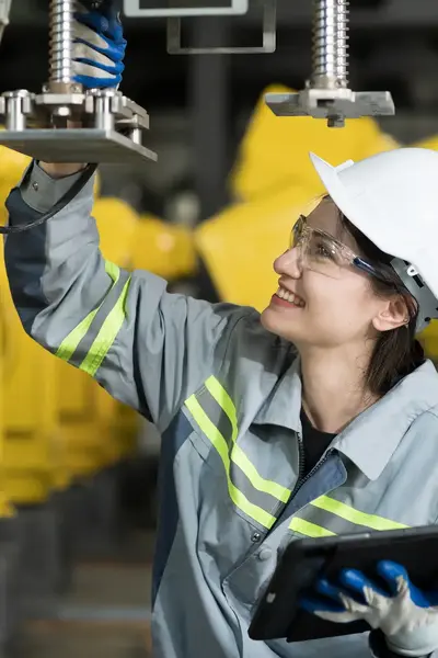 Student in overall met helm en veiligheidsbril sleutelt aan metalen machine