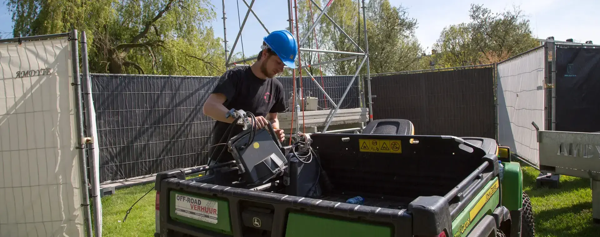 Man met terreinwagen en zwaar materiaal op een evenemententerrein.