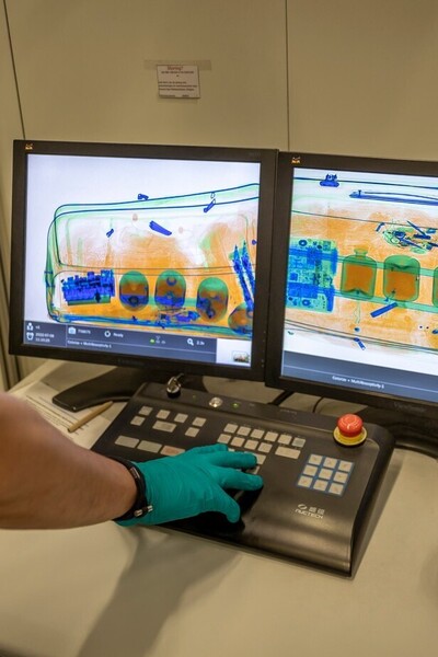 Douanier controleert inhoud koffer met scanner