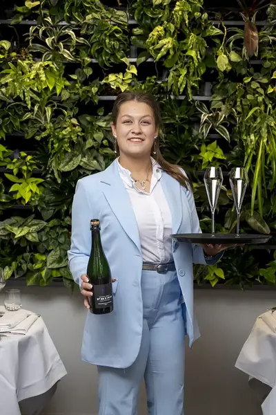 Paris Koeleman in blauw broekpak met fles en glazen