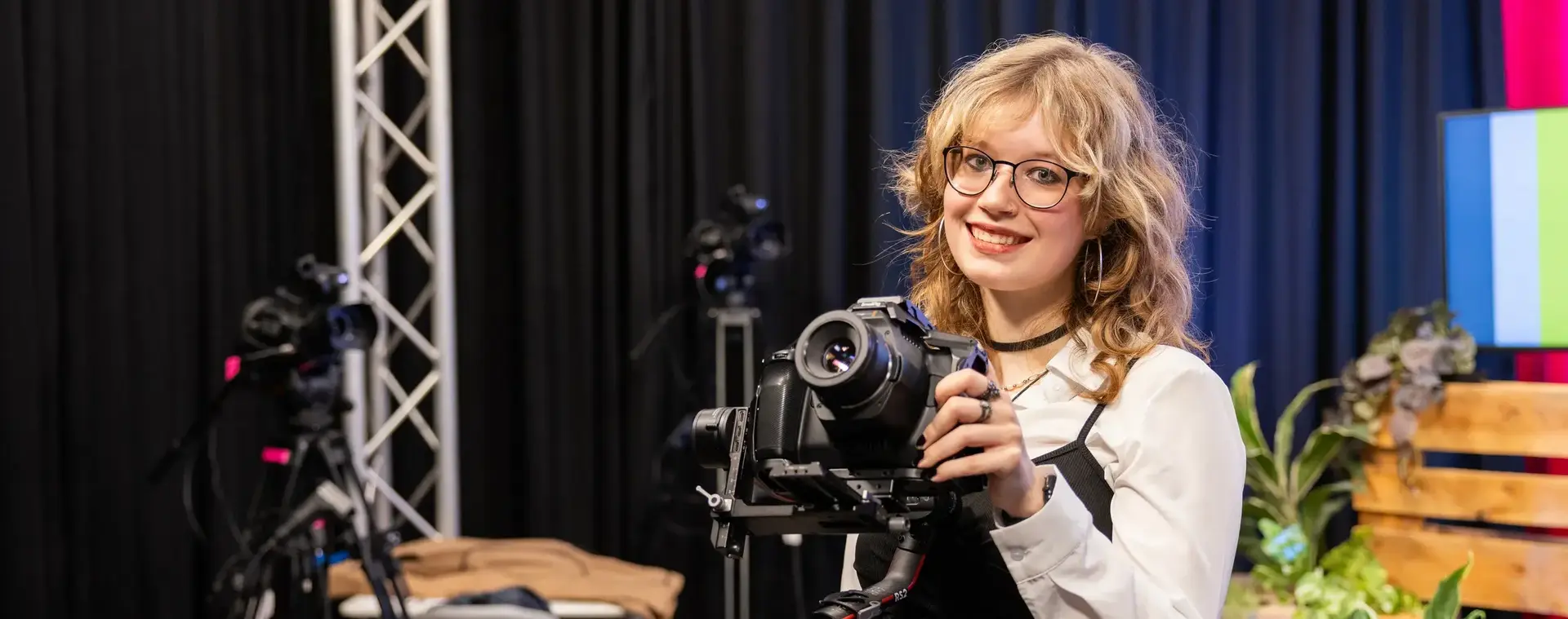 Mediastudent poseert in studio met camera