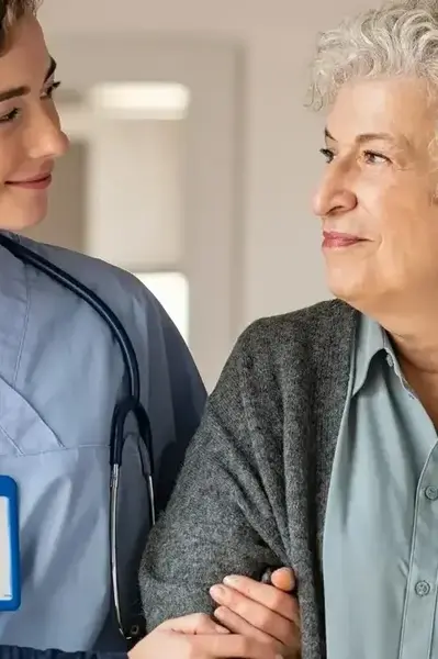 Verzorgende loopt gearmd met bejaarde vrouw