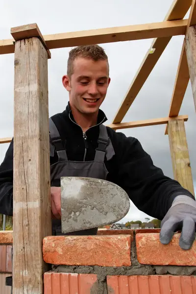 Metselaar metselt de muur van een gebouw