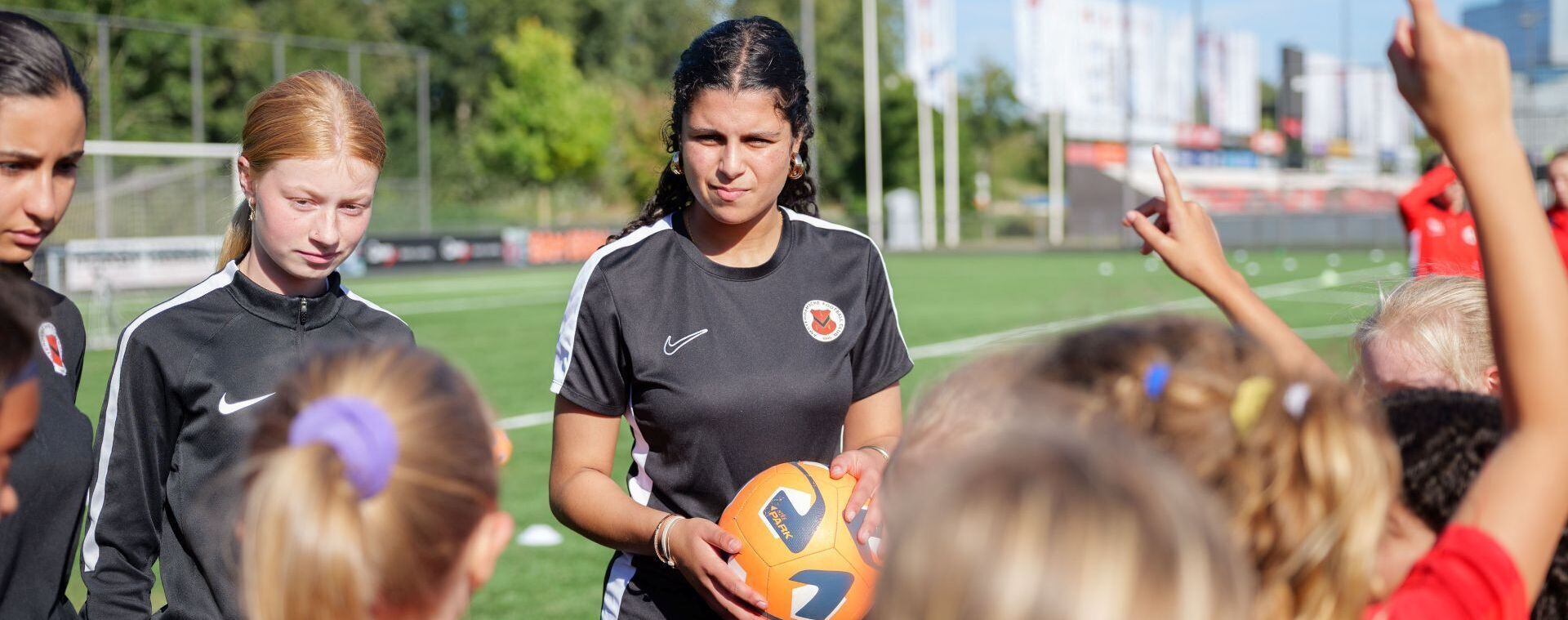 Voetbalcoach temidden van jonge pupillen op voetbalveld