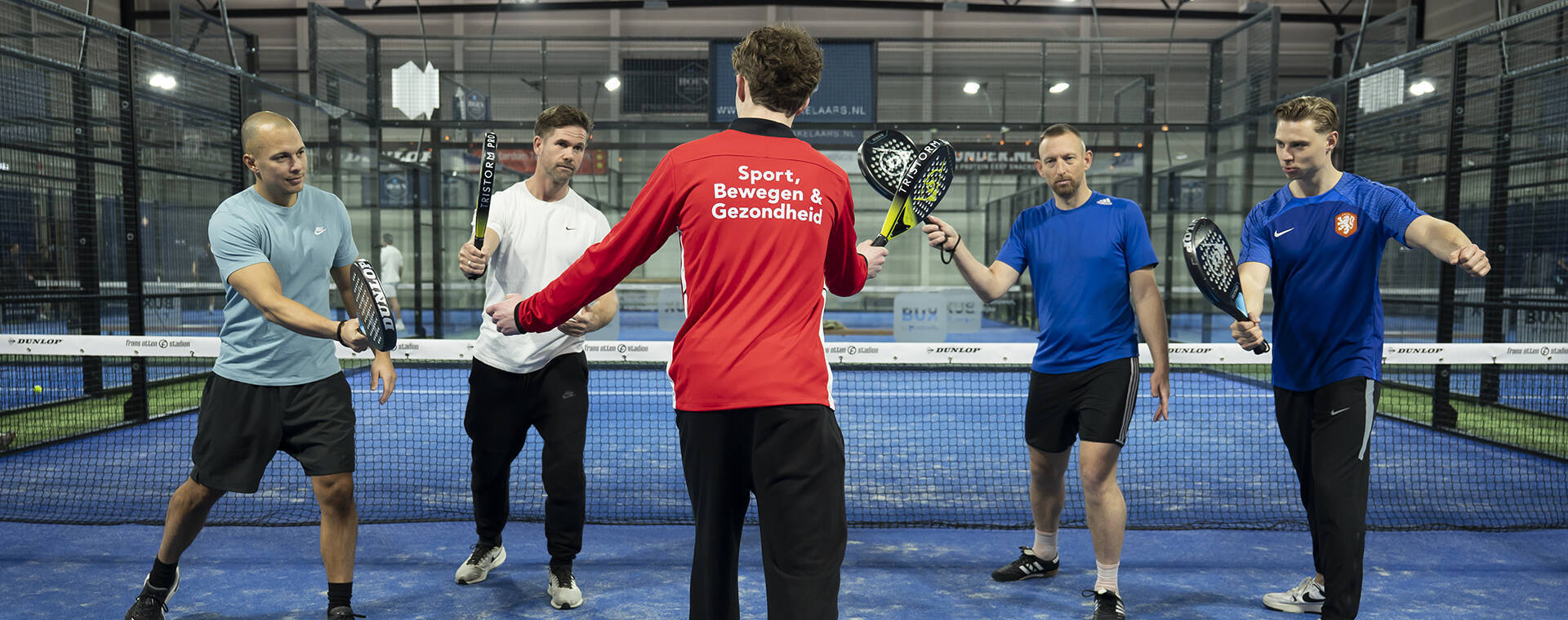 Mannen staan met tennisracket in de hand.