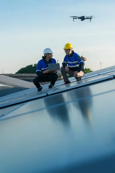 Onderhoudsmonteurs aan het werk op dak, met drone op de achtergrond