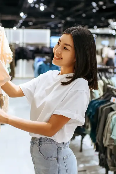 Student werkt in een kledingwinkel en helpt met het ordenen van de rekken.