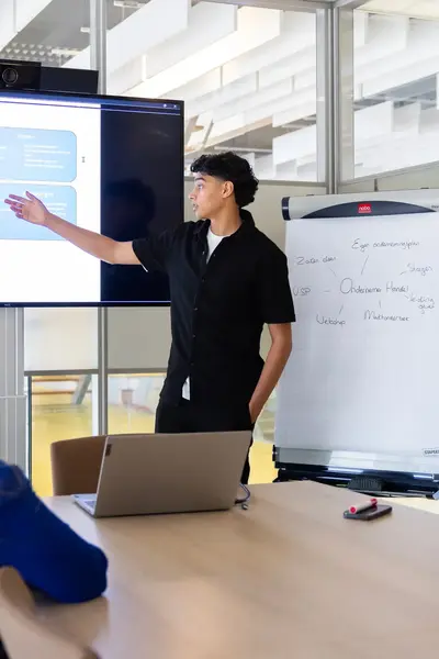 Student geeft presentatie aan twee personen aan vergadertafel