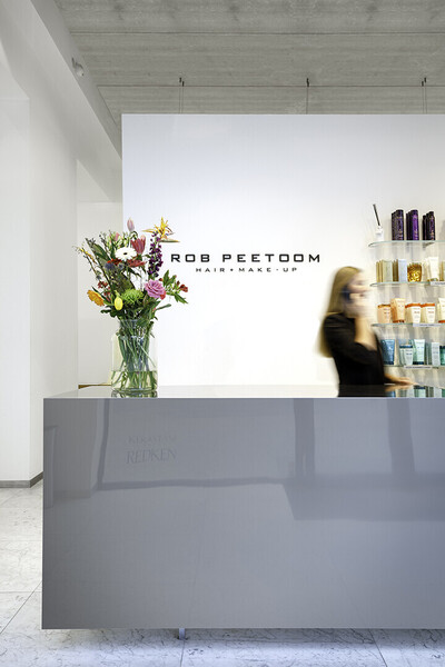 Vrouw telefoneert achter balie van kapsalon Rob Peetoom