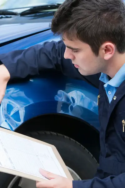 Inspecteur inspecteert schade aan voorkant auto
