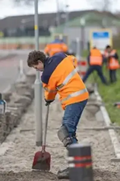 Straatmakers in oranje veiligheidsjassen buiten aan het werk, een straat aan het maken