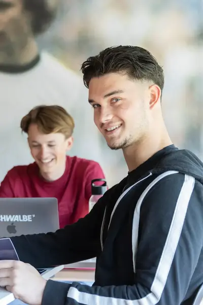 Groep studenten werkt samen achter laptops.