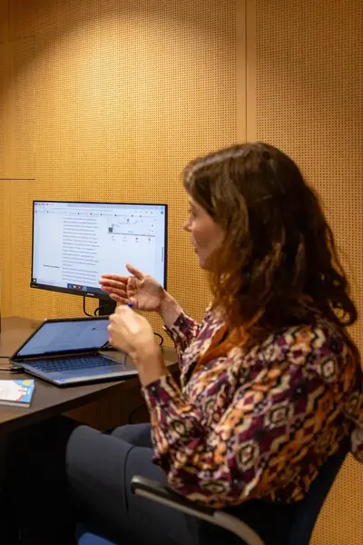 Drie vrouwen in overleg aan een tafel met laptops en notities.