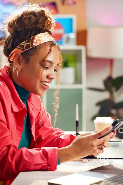 Studente achter bureau kijkend naar haar mobiel.
