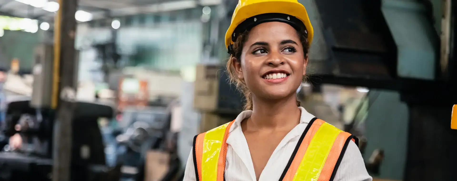 Vrouw in fluorescerend hesje met helm en tablet in fabriek