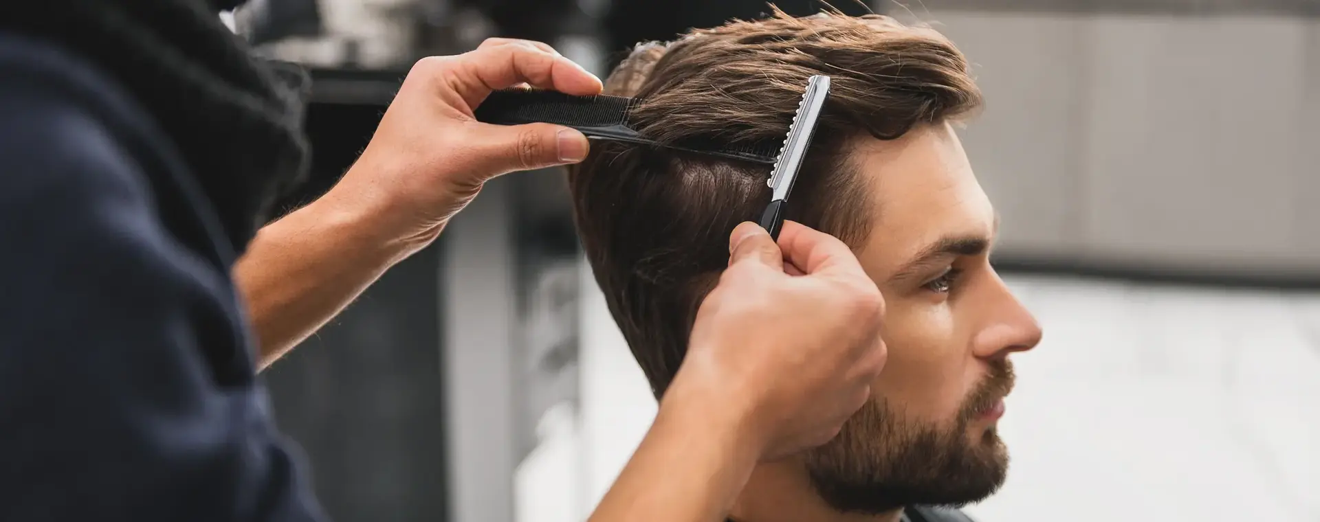 Kapster knipt het haar van een man met een tondeuse en kam in een moderne kapsalon. De klant zit stil terwijl het haar nauwkeurig in model wordt gebracht.