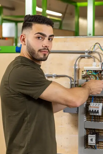Jonge man is aan het werk aan de elektra bij een stoppenkast.