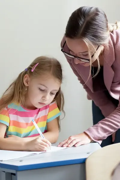 Meisje krijgt in de les hulp van lerares in klaslokaal 
