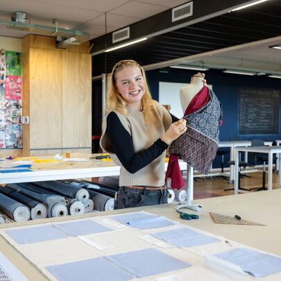 Fashion-student toont kledingstuk op paspop in modeatelier
