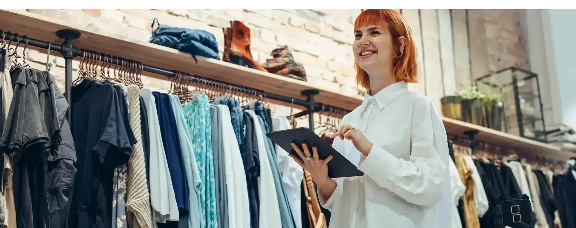 Kledingverkoopster met tablet in hand in winkel