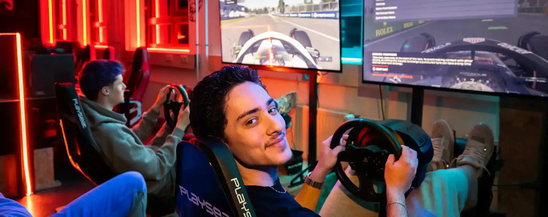 Twee jongens die een race game doen op grotere schermen. 