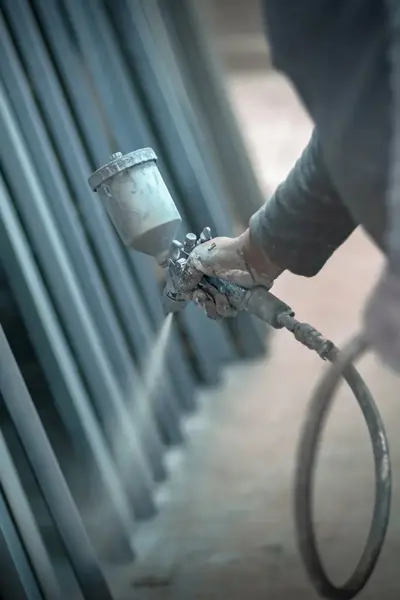 Coating specialistspuit verf op metalen objecten.