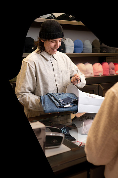 Verkoper stopt nieuwe spijkerbroek in papieren draagtas