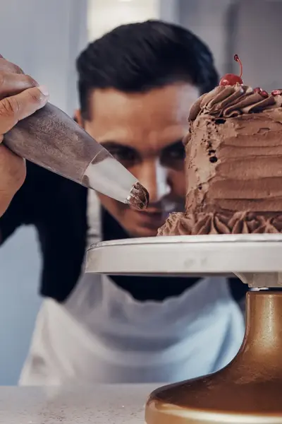 Banketbakker bewerkt chocoladetaart met spuitzak