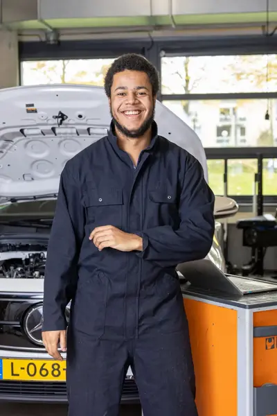 Student automonteur staat voor auto met open motorkap
