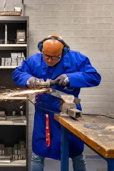 Man in overall met veiligheidsbril last metalen voorwerp