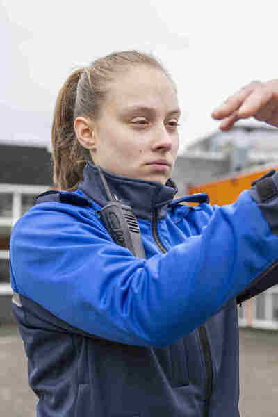 Studente in uniform slaat arrestant in boeien.  