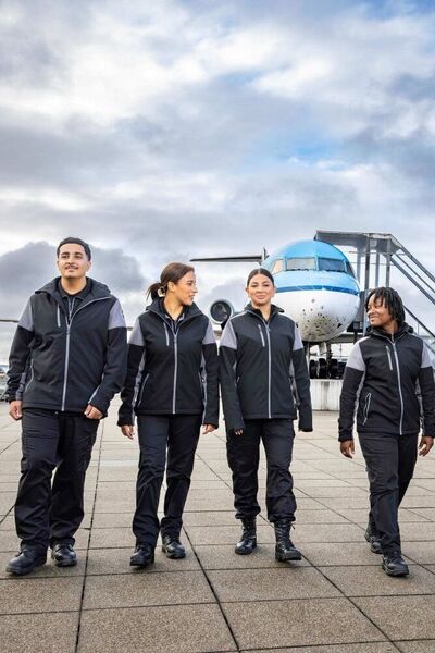 Studenten Luchthavenbeveiliger lopen over Schiphol met KLM-vliegtuig op de achtergrond