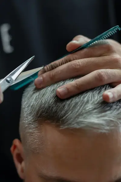 Close-up van een man die wordt geknipt door kapper.