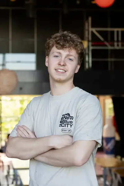 Jongen met zijn armen over elkaar met op de achtergrond tafels.