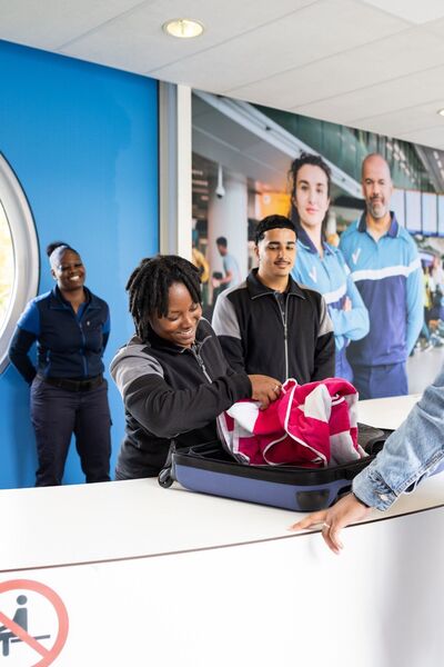 Studenten Luchthavenbeveiliger controleren inhoud tas in ontvangsthal