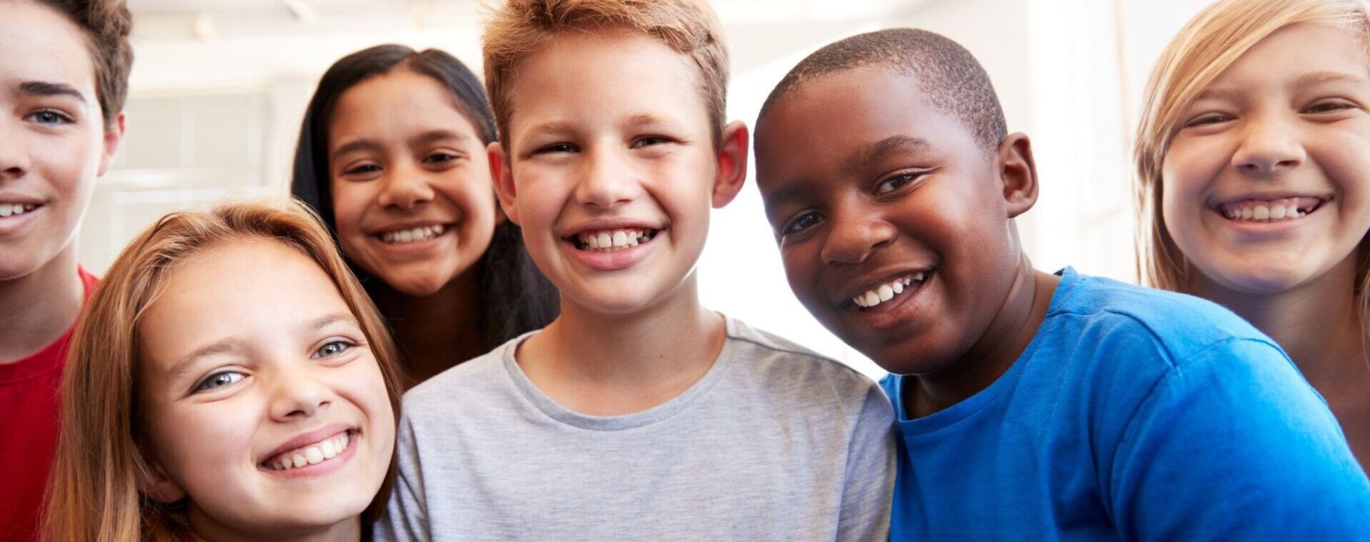 Zes kinderen kijken lachend de camera in