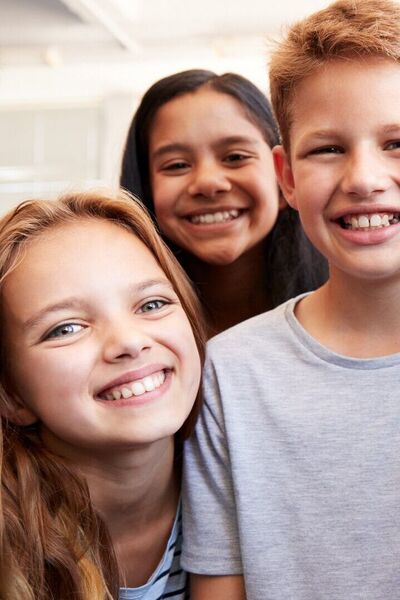 Zes kinderen kijken lachend de camera in