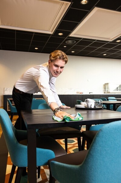 Student maakt tafels schoon in kantine