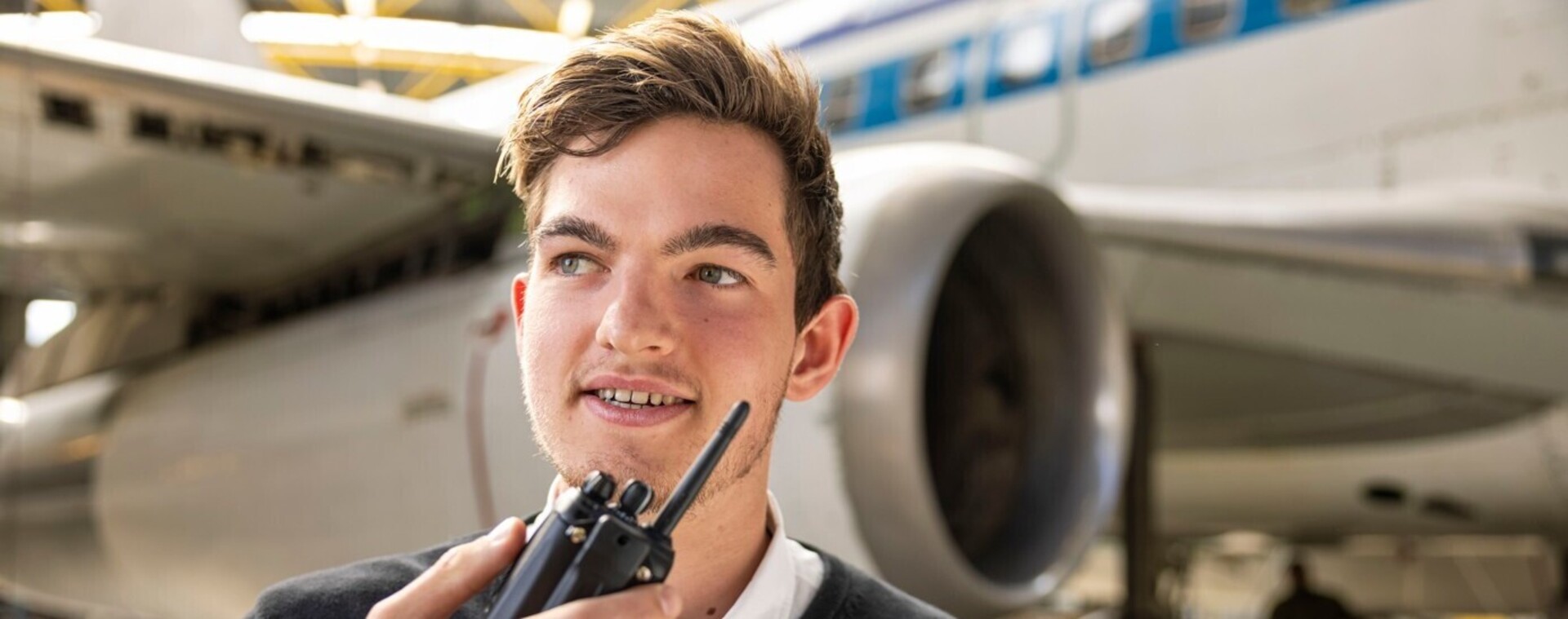 Student veiligheid in uniform en met portofoon staat voor vliegtuig