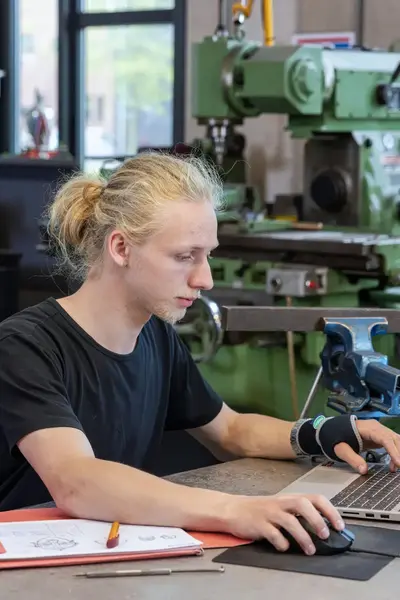 Student achter computer omringd door technische apparatuur
