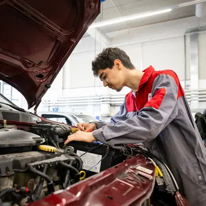 Student in ROCvA-overall checkt auto onder de motorkap.