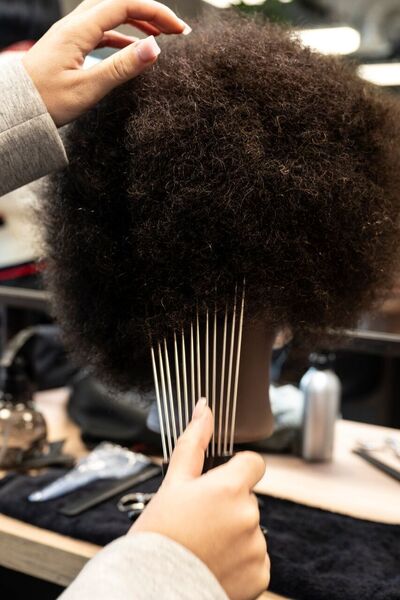 Student Haarverzorging kamt pruik in praktijklokaal