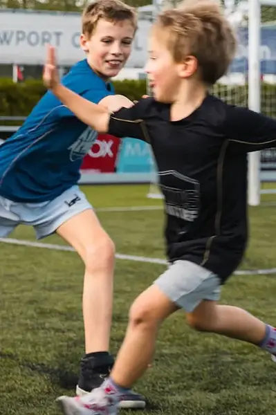 Coach geeft twee voetballertjes een high-five.