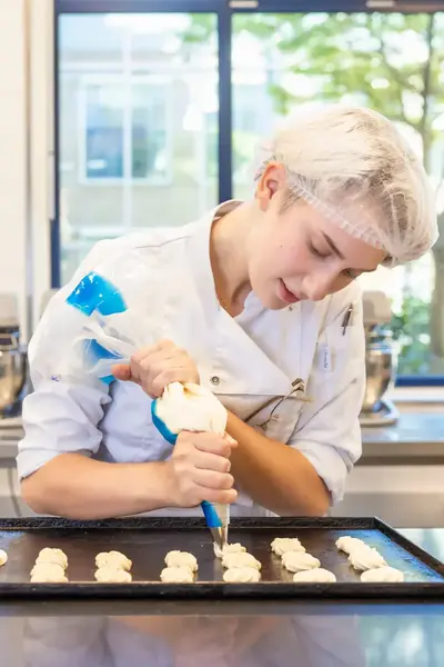Patissier werkt geconcentreerd aan een bakopdracht in een patisserie keuken
