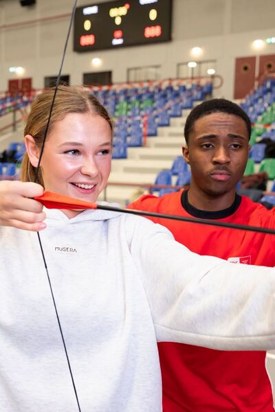 Student geeft les boogschieten in sportzaal