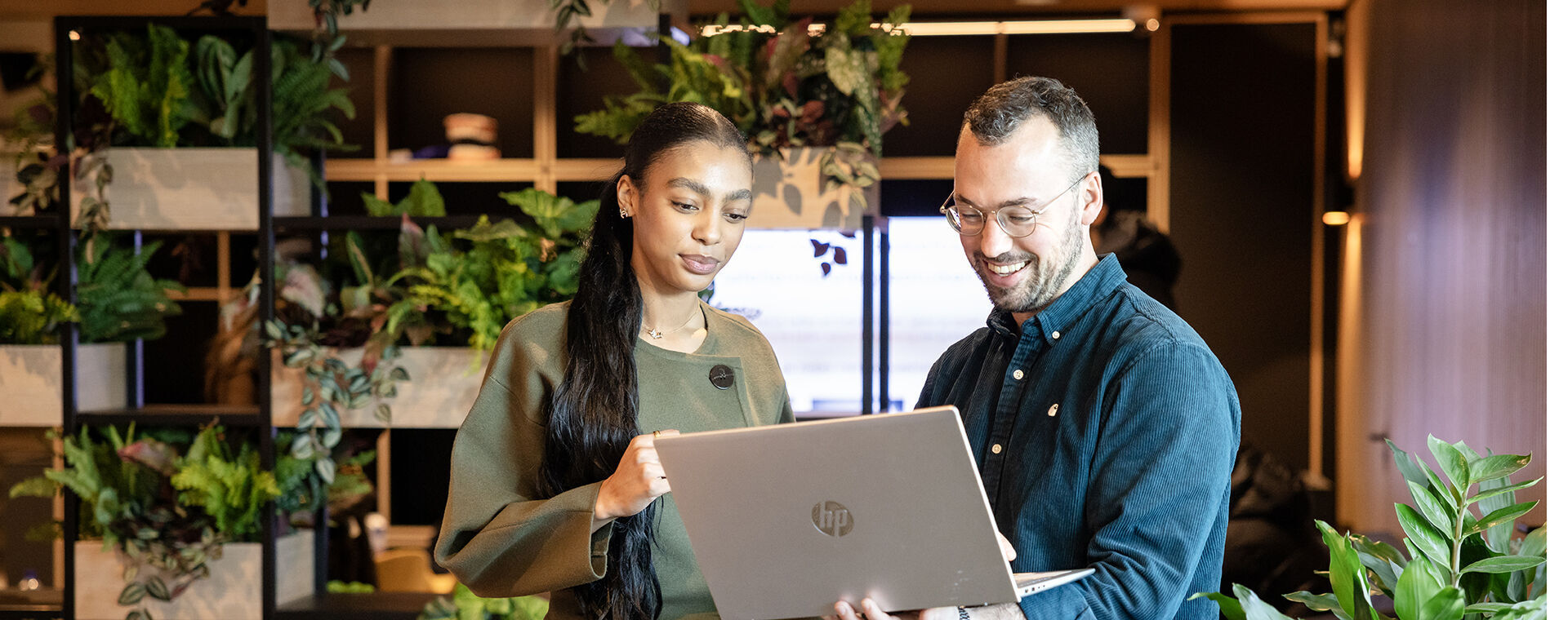 Man en vrouw kijken naar een in de hand gehouden laptop in een informele omgeving.