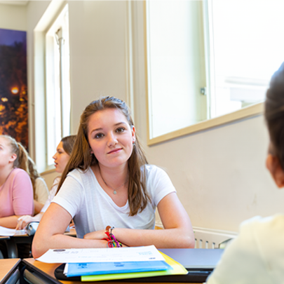 Een student zit in een klaslokaal en kijkt aandachtig.