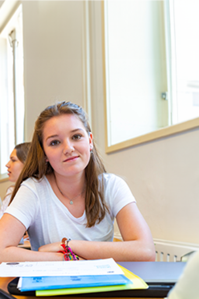 Een student zit in een klaslokaal en kijkt aandachtig.