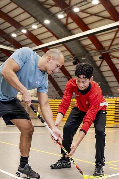 Student en leraar spelen een potje indoorhockey.